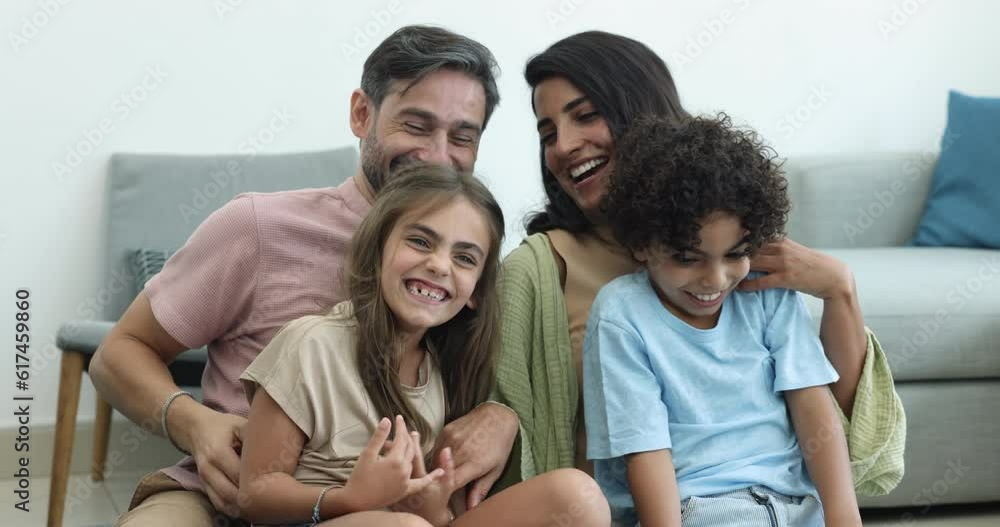 Happy married multinational couple pose for photo with cute siblings, tickling, laughing having fun sit on couch. Affectionate bonding multiethnic family enjoy leisure time at home. Playtime, custody Happy married multinational couple pose for photo with cute siblings, tickling, laughing having fun sit on couch. Affectionate bonding multiethnic family enjoy leisure time at home. Playtime, custody
