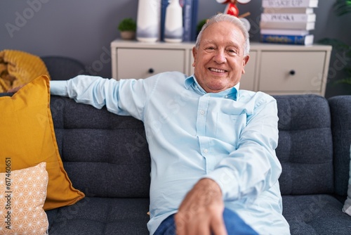 Middle age grey-haired man smiling confident sitting on sofa at home