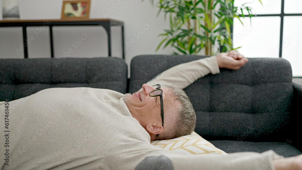 Middle age grey-haired man relaxed on sofa at home Middle age grey-haired man relaxed on sofa at home