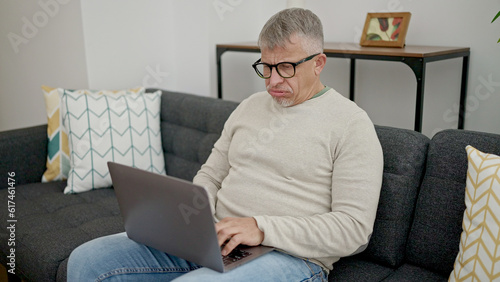 Wallpaper Mural Middle age grey-haired man using laptop with stressed expression at home Torontodigital.ca