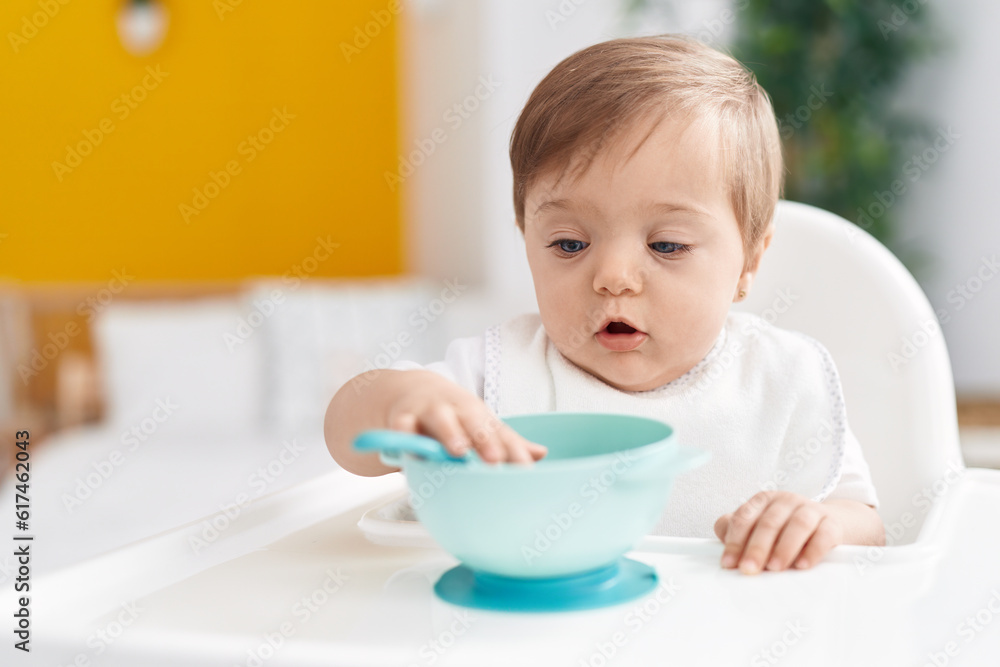 Adorable caucasian baby sitting on highchair holding spoon at bedroom Adorable caucasian baby sitting on highchair holding spoon at bedroom
