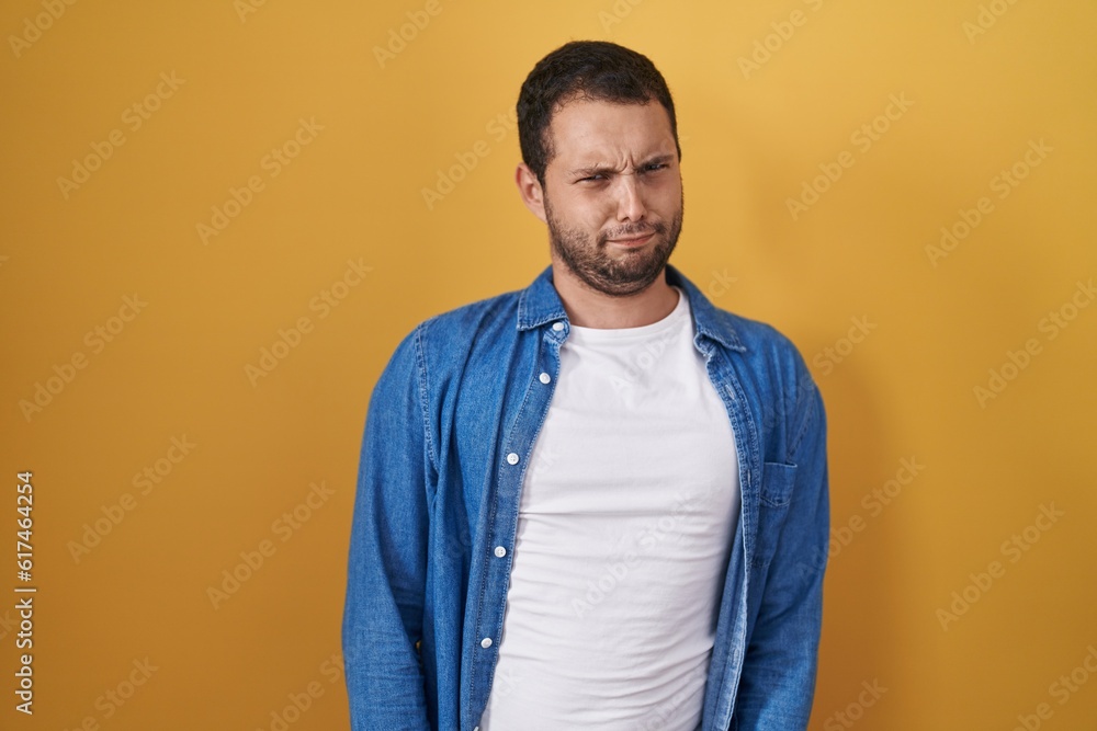 Hispanic man standing over yellow background skeptic and nervous, frowning upset because of problem. negative person. Hispanic man standing over yellow background skeptic and nervous, frowning upset because of problem. negative person.