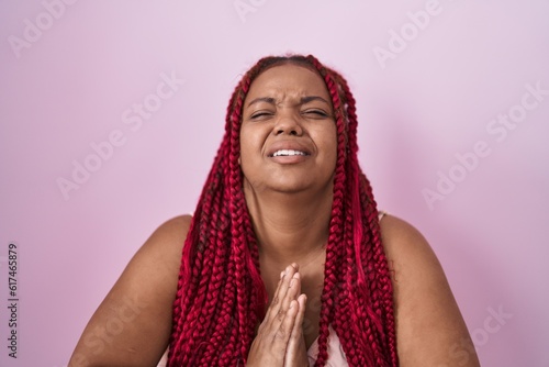 African american woman with braided hair standing over pink background begging and praying with hands together with hope expression on face very emotional and worried. begging. © Krakenimages.com
