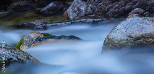 River water flows over rocks in rapids captured in slow motion in the tropical cloud forest. Milky appearance. Slow motion water running through the forest among the jungle. Slow shutter speed.