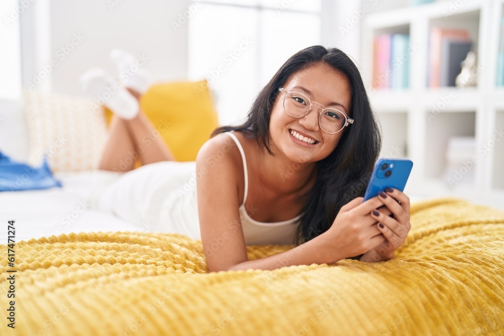 Young chinese woman using smartphone lying on bed at bedroom Young chinese woman using smartphone lying on bed at bedroom