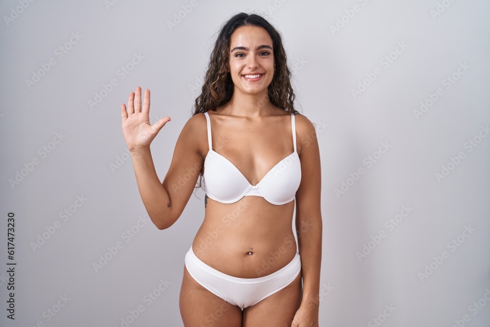 Young hispanic woman wearing white lingerie showing and pointing up with fingers number five while smiling confident and happy. Young hispanic woman wearing white lingerie showing and pointing up with fingers number five while smiling confident and happy.