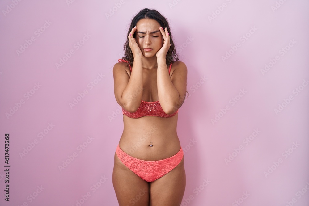 Young hispanic woman wearing lingerie over pink background with hand on head, headache because stress. suffering migraine. Young hispanic woman wearing lingerie over pink background with hand on head, headache because stress. suffering migraine.