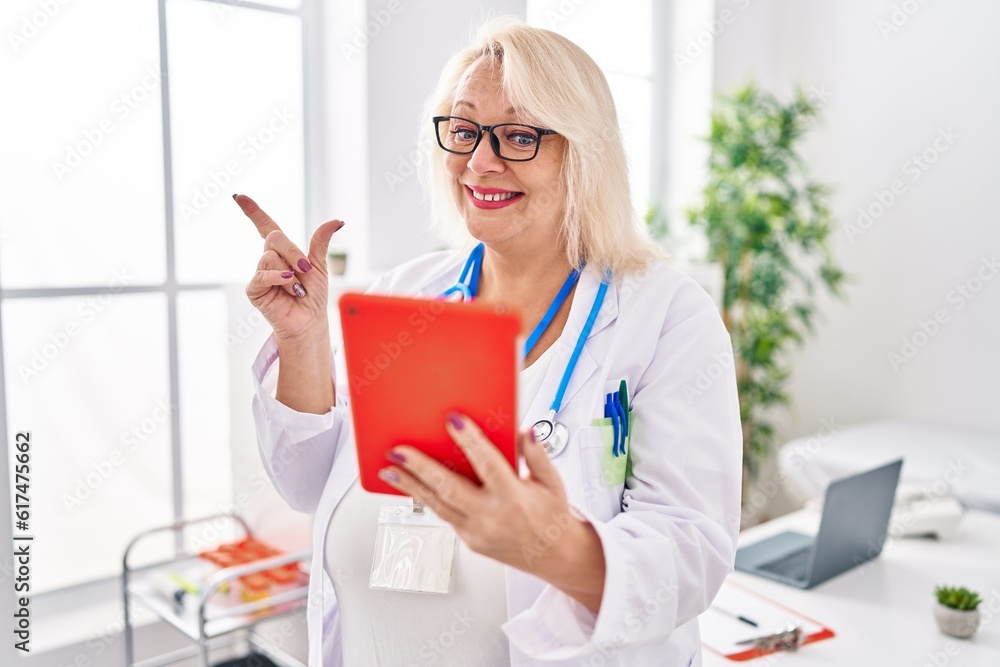 Middle age caucasian woman working on online appointment smiling happy pointing with hand and finger to the side Middle age caucasian woman working on online appointment smiling happy pointing with hand and finger to the side