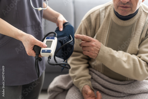 Smiling young nurse taking old man's blood pressure