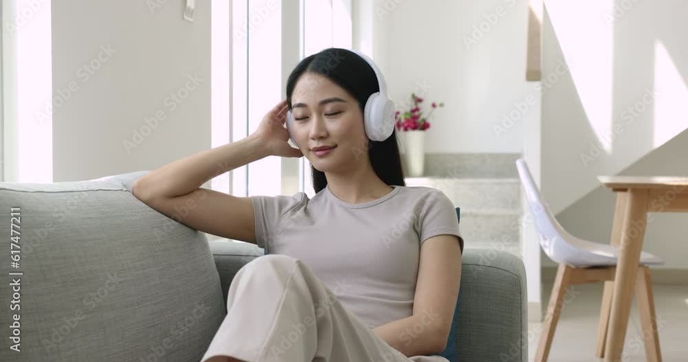 Carefree young beautiful woman sit on cozy couch in headphones enjoy favorite music or listen audiobook with closed eyes, spend weekend time alone at home after hard work day. Time to relax, chill out Carefree young beautiful woman sit on cozy couch in headphones enjoy favorite music or listen audiobook with closed eyes, spend weekend time alone at home after hard work day. Time to relax, chill out