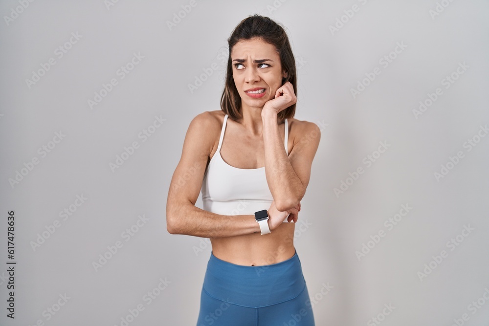 Hispanic woman wearing sportswear over isolated background thinking worried about a question, concerned and nervous with hand on chin Hispanic woman wearing sportswear over isolated background thinking worried about a question, concerned and nervous with hand on chin