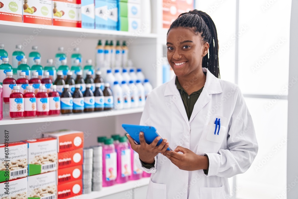 African american woman pharmacist using touchpad working at pharmacy