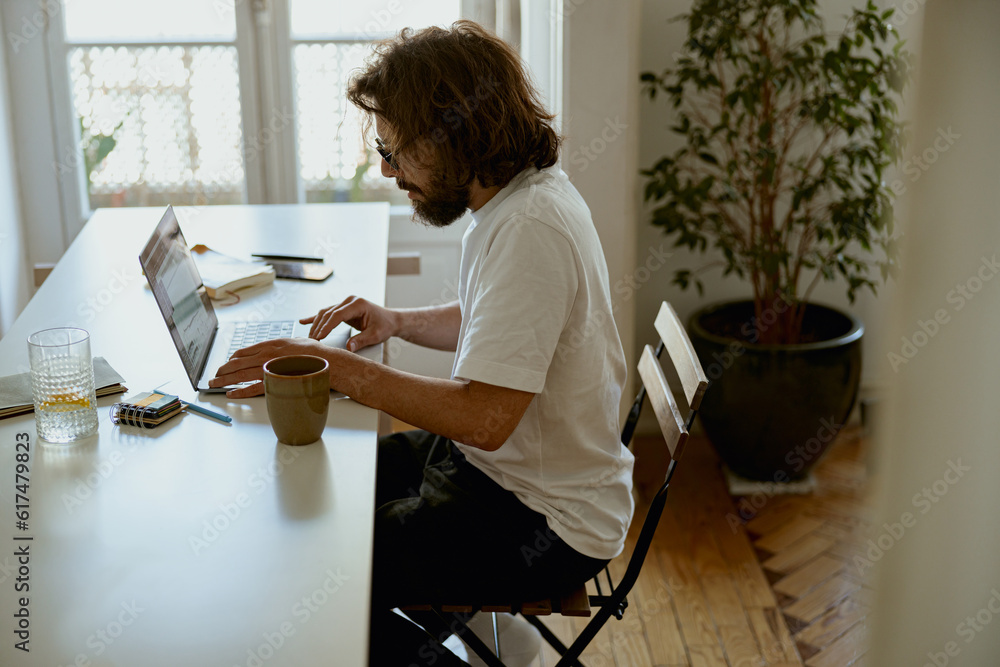 Young man freelancer sitting at home and working on laptop online. Remote work concept Young man freelancer sitting at home and working on laptop online. Remote work concept