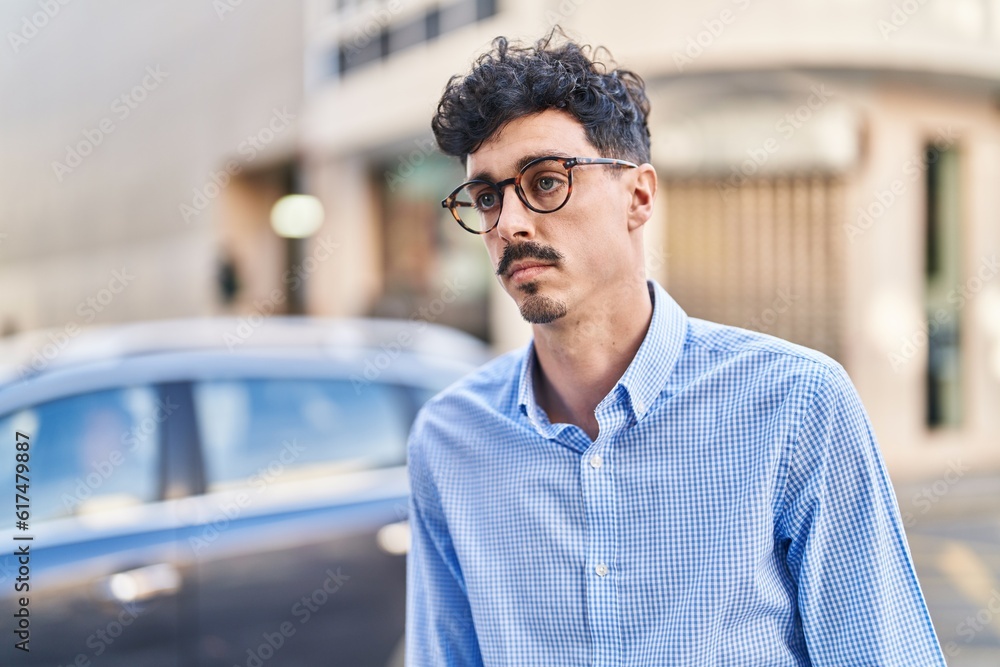 Young caucasian man looking to the side with serious expression at street Young caucasian man looking to the side with serious expression at street
