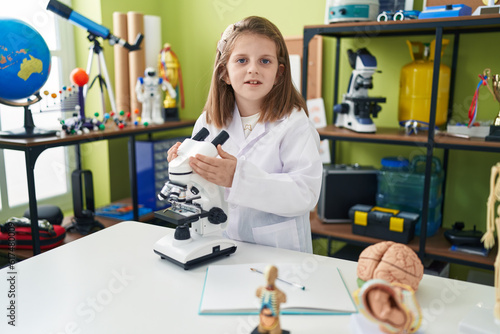 Adorable blonde girl student smiling confident using microscope at laboratory classroom