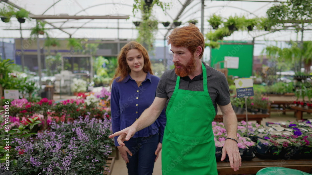Redhead Man in Green Apron Assisting Female Customer in Local Flower Shop Redhead Man in Green Apron Assisting Female Customer in Local Flower Shop