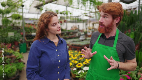 Male Florist at Flower Shop wearing Green Apron helping Female Customer in Local Business Store © Marco