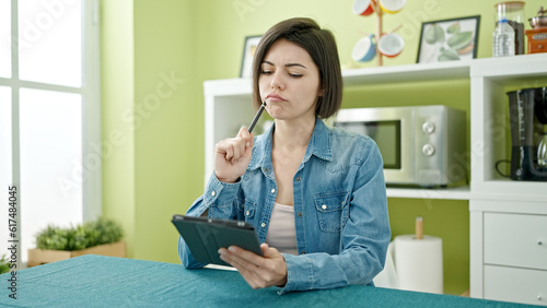Young caucasian woman using touchpad sitting on table at home