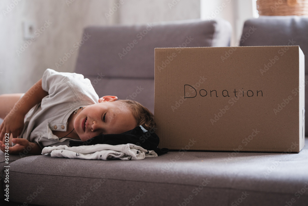 Cardboard donation box and baby kid. Little child helping to sort