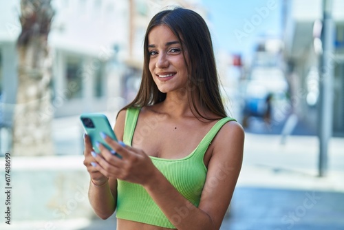 Young beautiful hispanic woman smiling confident using smartphone at street