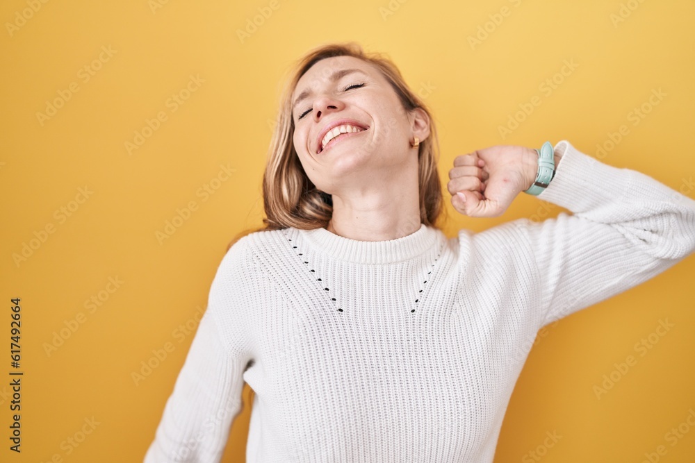 Young caucasian woman wearing white sweater over yellow background stretching back, tired and relaxed, sleepy and yawning for early morning Young caucasian woman wearing white sweater over yellow background stretching back, tired and relaxed, sleepy and yawning for early morning