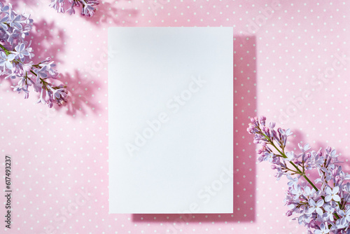 Mockup white greeting card with lilac branches on a pink background
