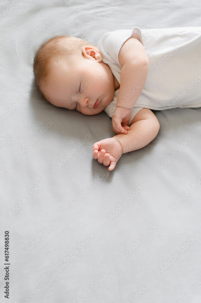Cute baby sleeps peacefully in his crib at home, lying on his side.The concept of independent sleep,childhood protection Cute baby sleeps peacefully in his crib at home, lying on his side.The concept of independent sleep,childhood protection