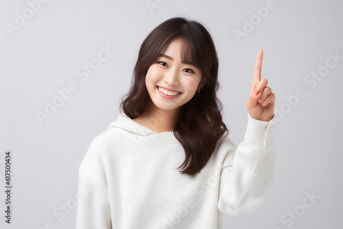 Pointing finger of an Asian girl highlights vacant space on a white background, making it a prime choice for a promotional advertising banner. Generative AI.