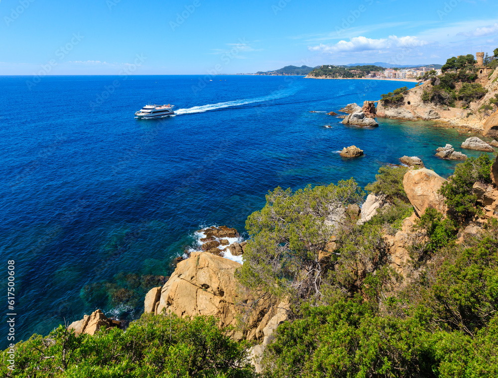 Summer sea rocky coast view with Castle of Sant Joan and boat (Lloret de Mar town, Catalonia, Spain).
