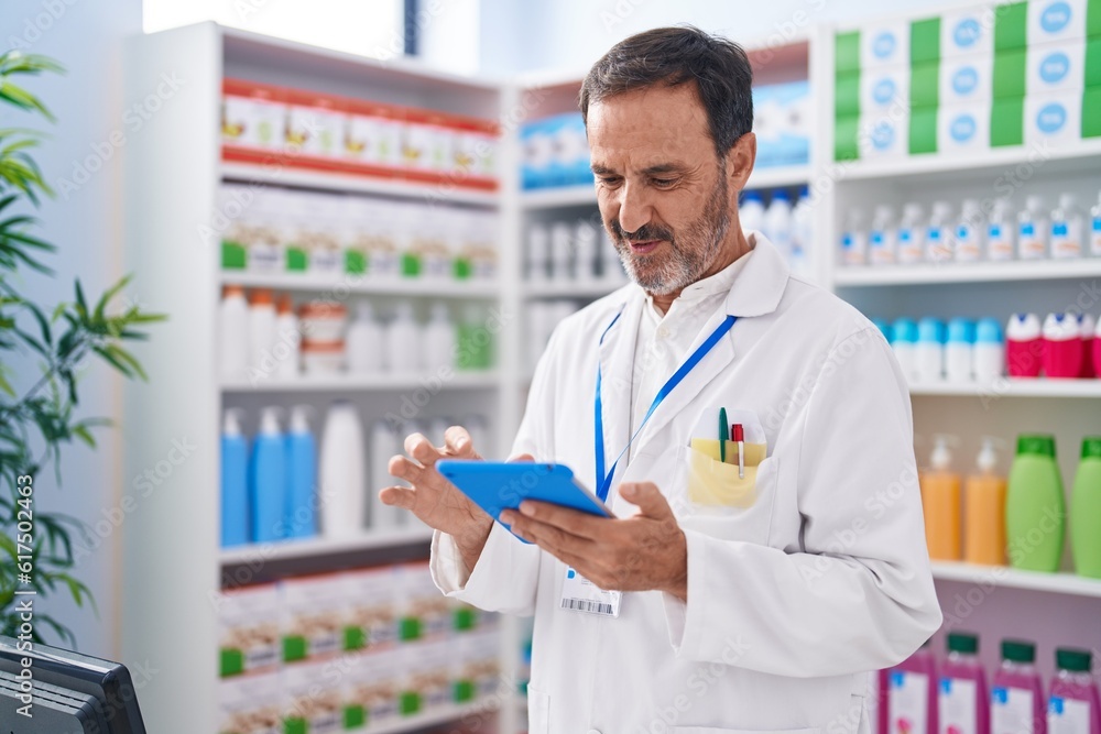 Middle age man pharmacist using touchpad working at pharmacy Middle age man pharmacist using touchpad working at pharmacy