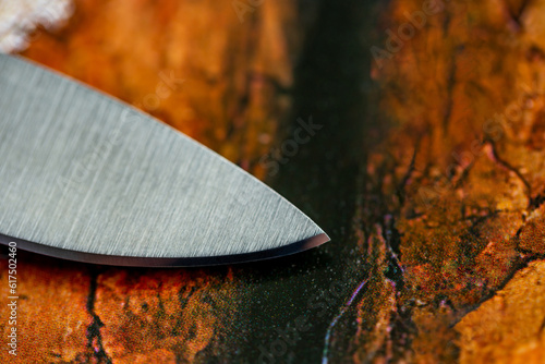 Cutting edge of kitchen knive closeup. Tip of knive on background of wooden surface