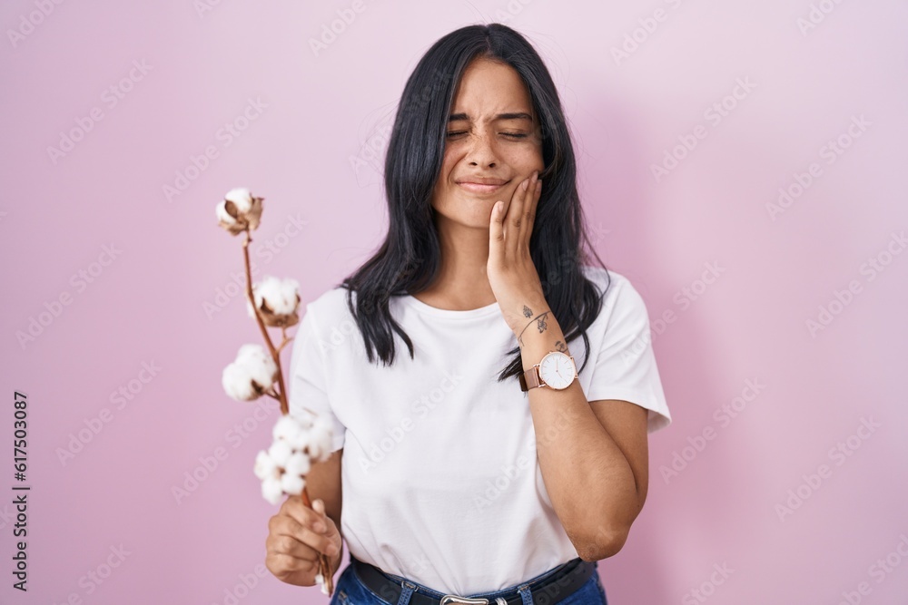 Brunette woman standing over pink background touching mouth with hand with painful expression because of toothache or dental illness on teeth. dentist concept.