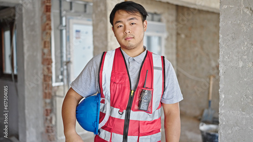  builder holding hardhat with relaxed expression at construction site