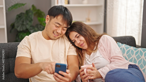 Man and woman couple using smartphone drinking coffee at home