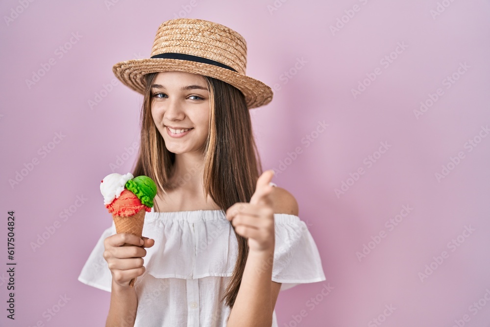 Teenager girl holding ice cream pointing fingers to camera with happy and funny face. good energy and vibes.