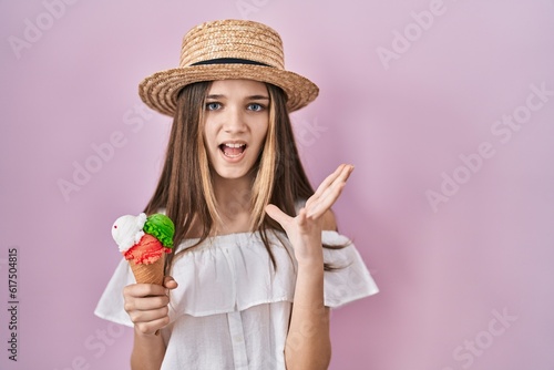 Teenager girl holding ice cream crazy and mad shouting and yelling with aggressive expression and arms raised. frustration concept.