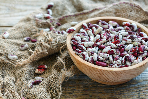 Fotografia Speckled beans in a wooden bowl on old rustic table.