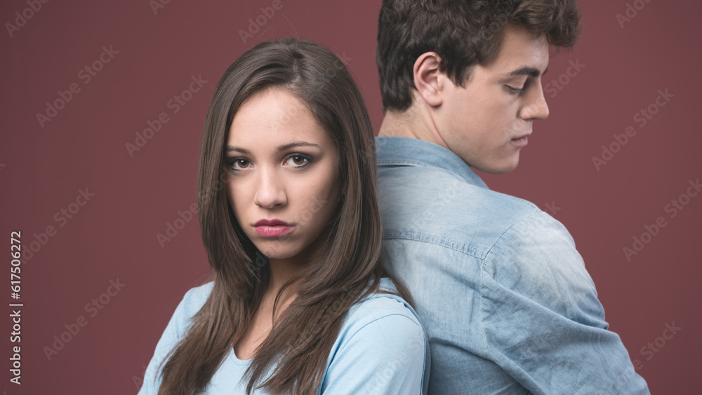 Young sad couple arguing and standing back to back Young sad couple arguing and standing back to back
