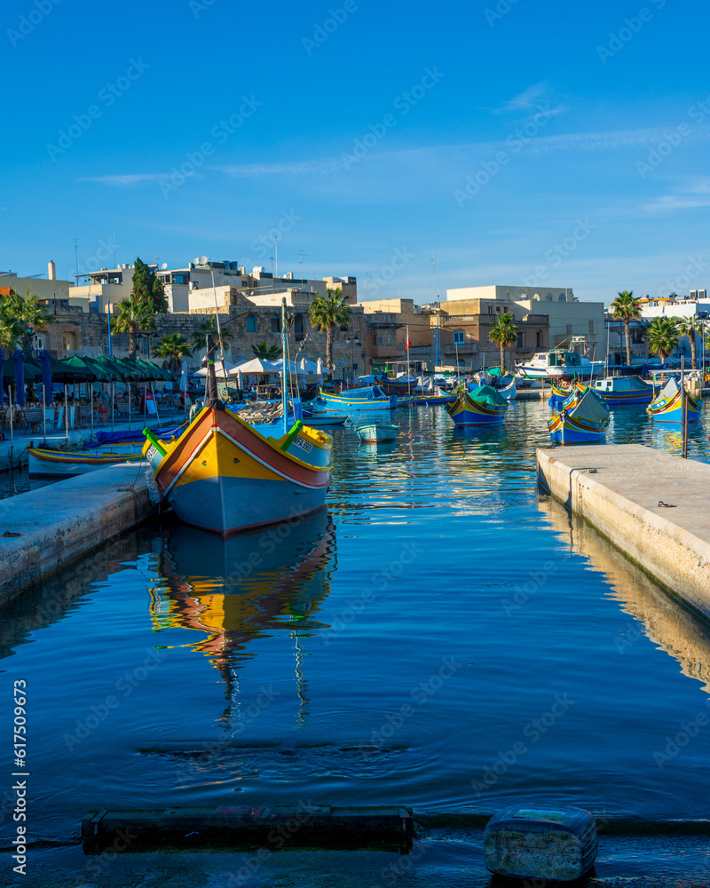 Fototapeta premium Colorful painted wood boats with the typical protective eyes on a sunny day in Marsaxlokk, Malta.