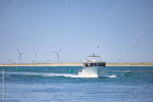 Foto Bateau entrant dans un port de pêche , bombardier, homards, ciel bleu, éoliennes