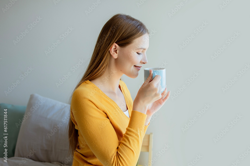 Young Woman Drinking Morning Coffee Sitting On Bed At Home Young Woman Drinking Morning Coffee Sitting On Bed At Home