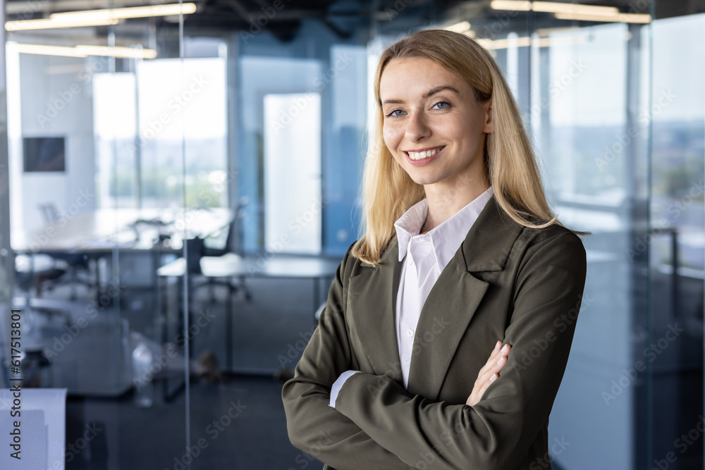 Portrait of a successful and smiling business woman, the founder of the company, the director in a suit standing confidently in the office. crossing his arms on his chest, looking at the camera Portrait of a successful and smiling business woman, the founder of the company, the director in a suit standing confidently in the office. crossing his arms on his chest, looking at the camera