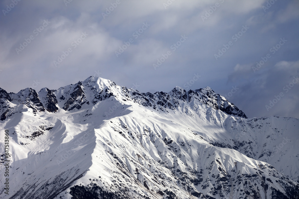 Snow sunlight mountain and cloudy sky at winter evening. Caucasus Mountains. Svaneti region of Georgia.