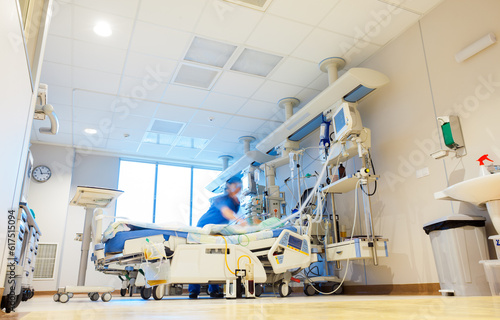 A hospital room with modern medical equipment and blurred patient and nurse or doctor figures.