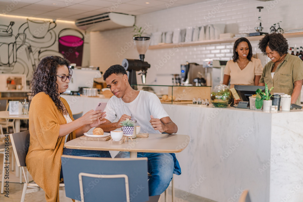 cliente brasileiros sentados na mesa de uma cafeteria no Brasil usando o celular para ver o cardápio virtual cliente brasileiros sentados na mesa de uma cafeteria no Brasil usando o celular para ver o cardápio virtual