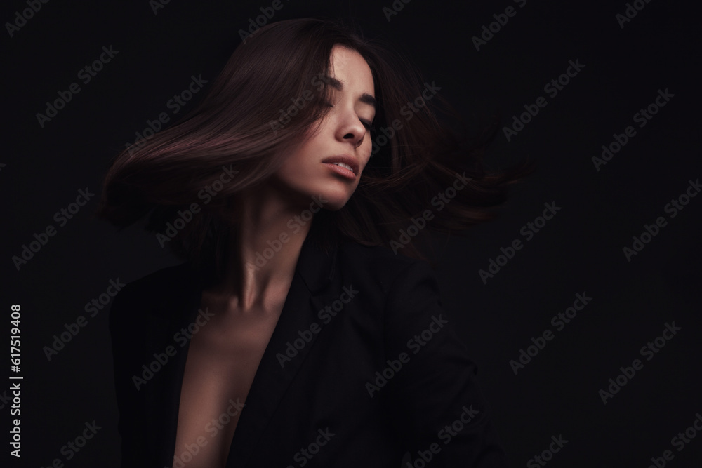 Portrait of a beautiful girl with flying brown hair over dark studio background
