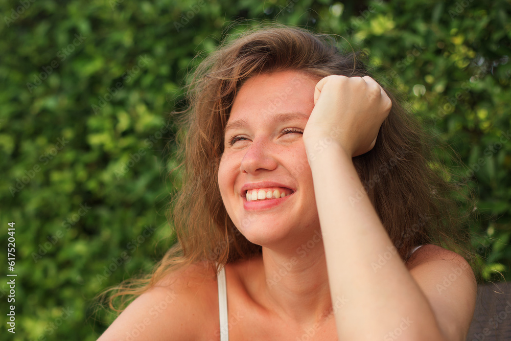 Portrait of happy beautiful young woman at sunny summer day smile and look at camera relax on natural background Portrait of happy beautiful young woman at sunny summer day smile and look at camera relax on natural background