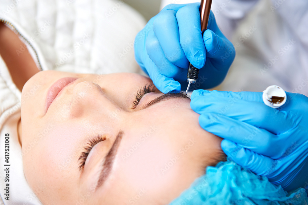 Permanent make-up master makes eyebrow correction procedure. Permanent makeup. Close-up. Permanent make-up master makes eyebrow correction procedure. Permanent makeup. Close-up.