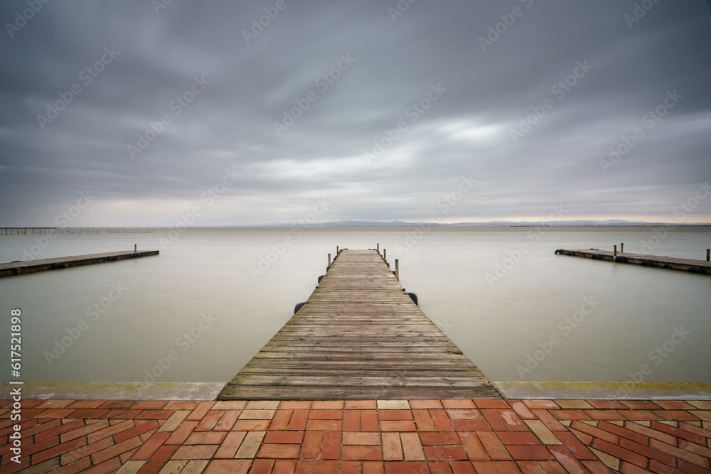 Long exposure with silk water and storm over Albufera with pier, Valencia