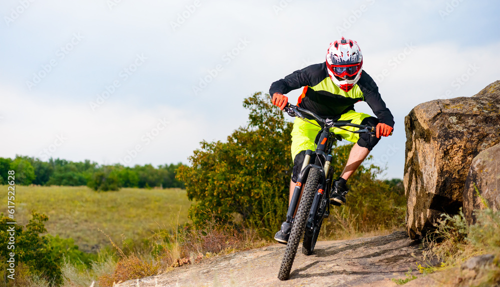 Professional Cyclist Riding the Bike at the Rocky Trail. Extreme Sport Concept. Free Space for Text. Professional Cyclist Riding the Bike at the Rocky Trail. Extreme Sport Concept. Free Space for Text.